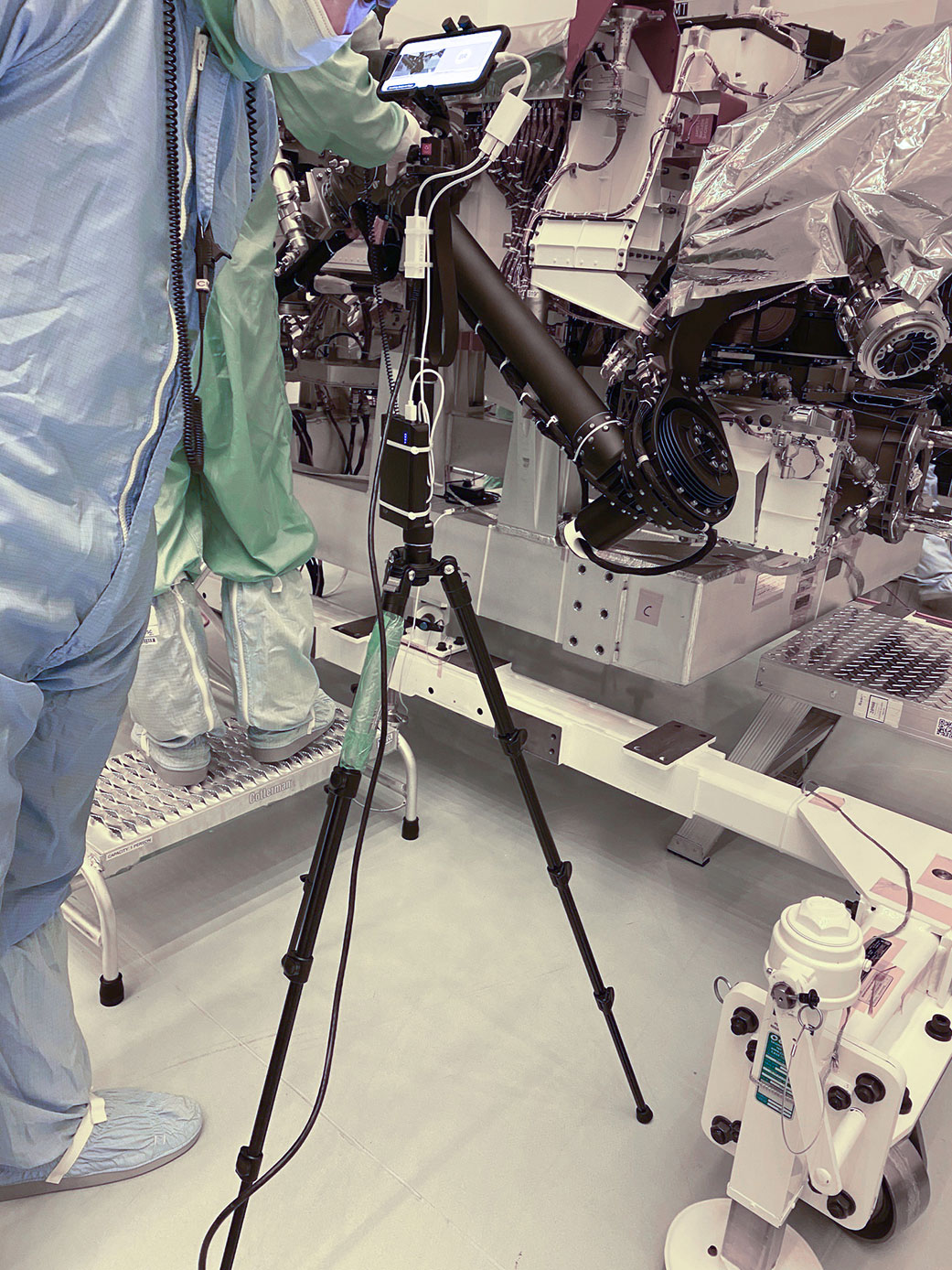 A technician points a smartphone camera at NASA's Perseverance rover during an inspection