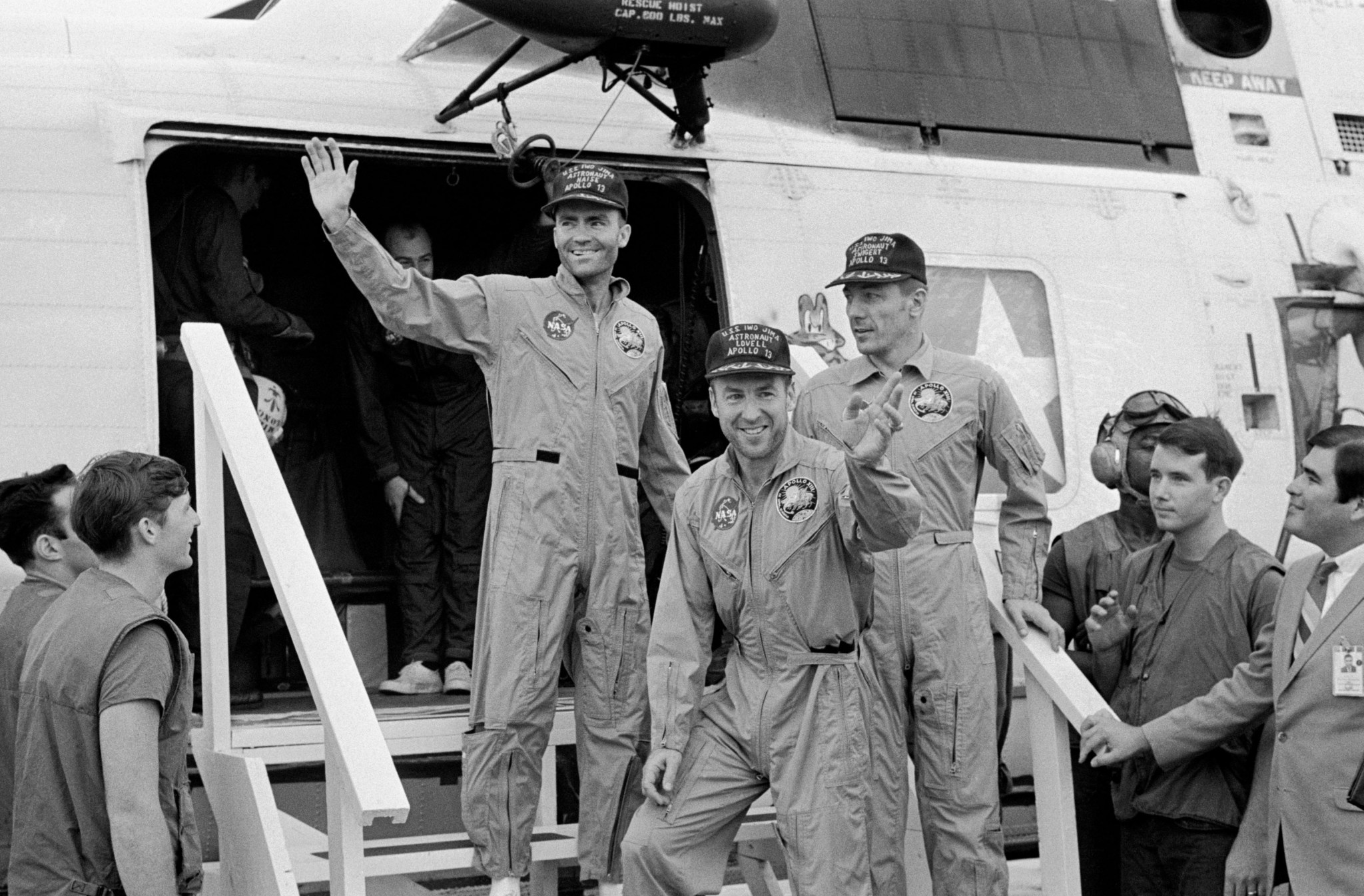 Three Apollo 13 crew members in flight suits wave while aboard USS Iwo Jima ship