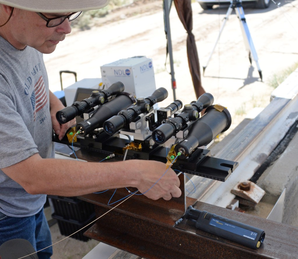 Bruce Barnes routes fiber optic cables from the navigation doppler lidar laser source to the instrument’s telescopes. Two telescopes, three sighting scopes, and a sighting camera are visible in this picture.