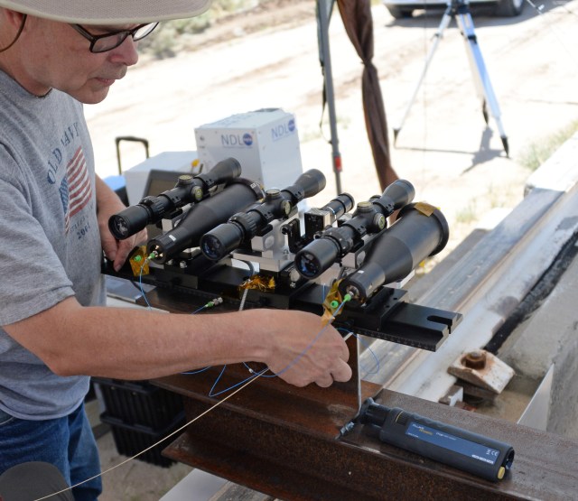 Bruce Barnes routes fiber optic cables from the navigation doppler lidar laser source to the instrument’s telescopes. Two telescopes, three sighting scopes, and a sighting camera are visible in this picture.