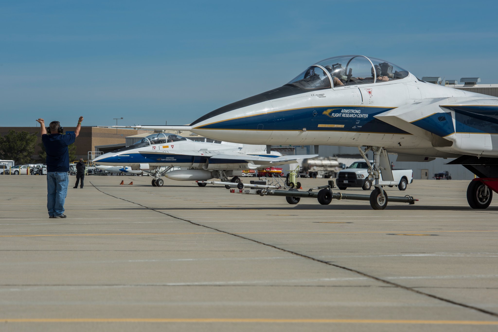 NASA F/A-18 in background, aviation maintenance crew chief Walt Kondracki guides a NASA F-15.