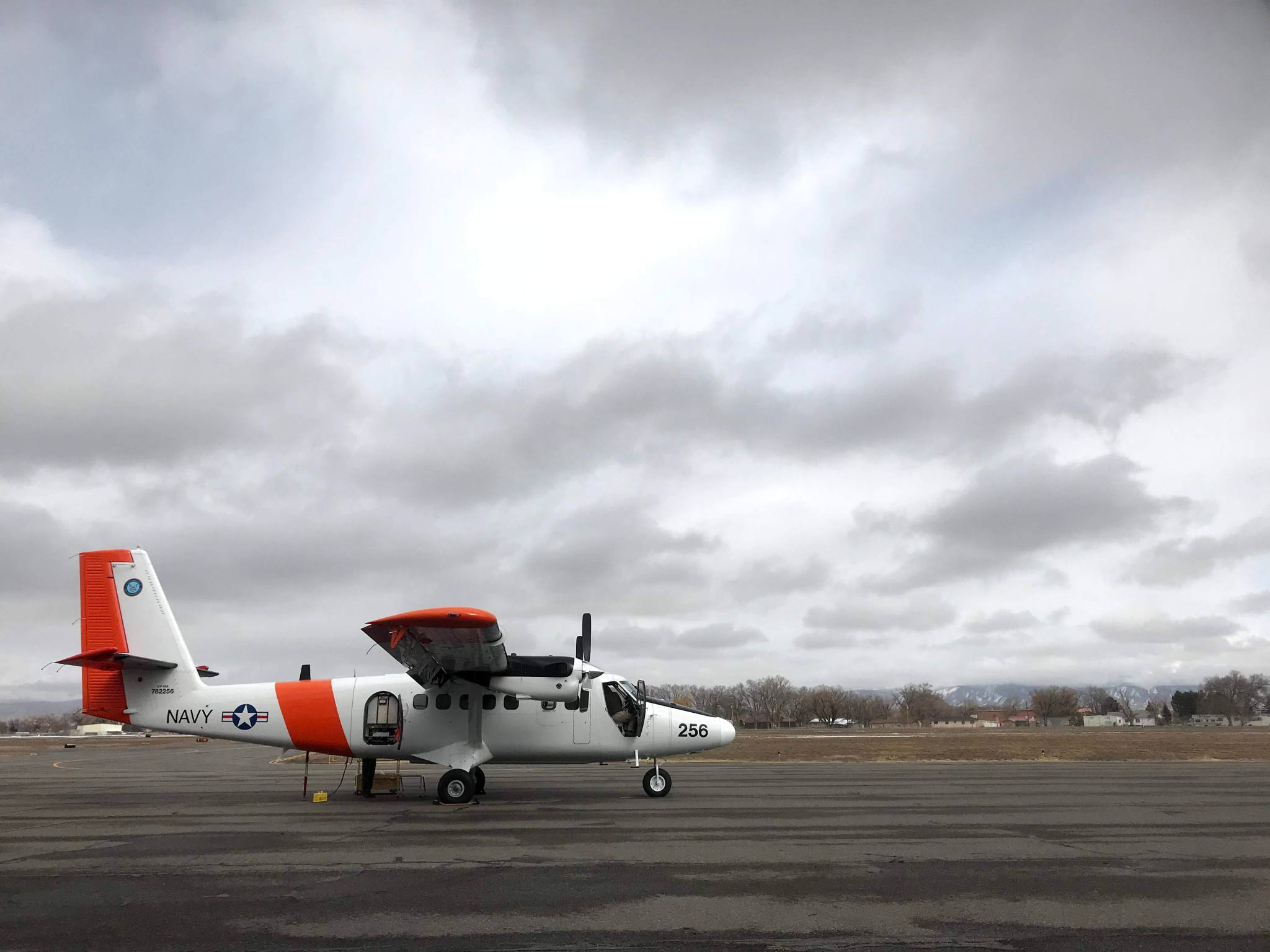 A DHC-6 Twin Otter sits on the runway under cloudy skies