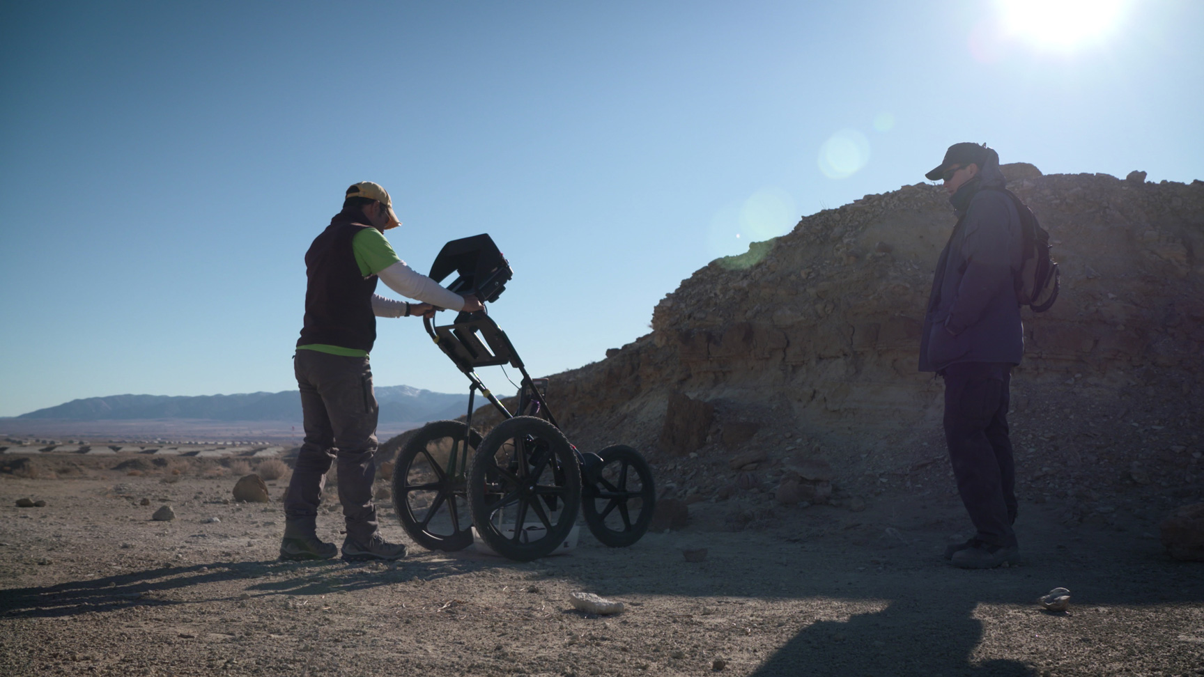 A member of a science field team operates a subsurface radar 