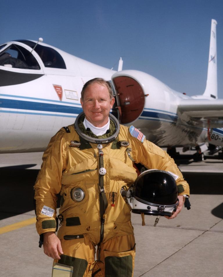 Man in spacesuit posed in front of aircraft.