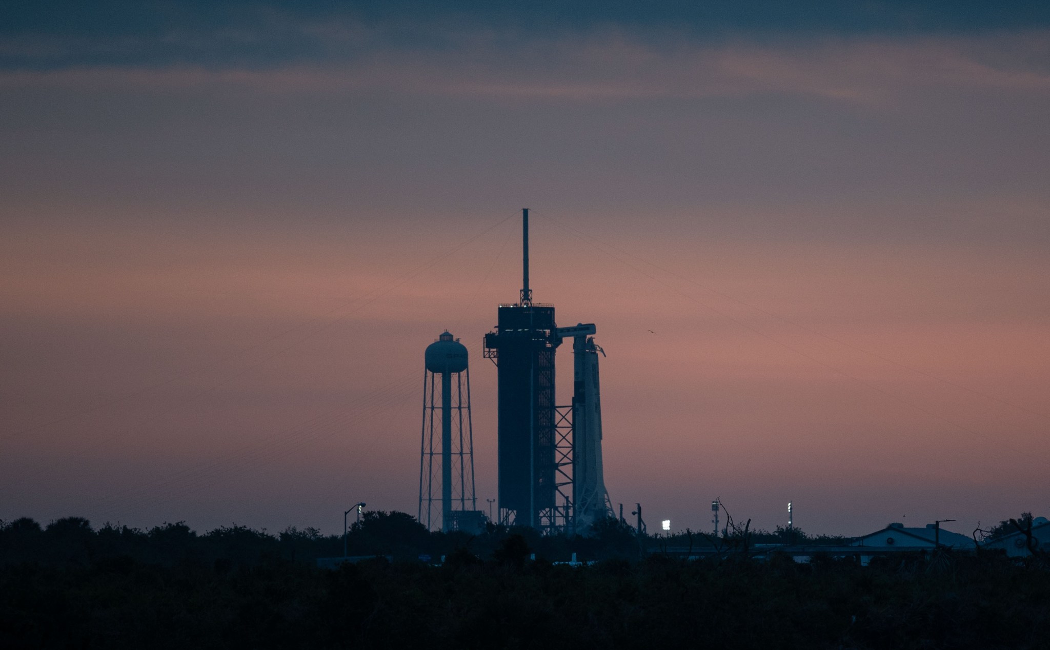 Image of the Crew Dragon spacecraft attached to a SpaceX Falcon 9 rocket on the launch pad at Launch Complex 39A at sunrise.