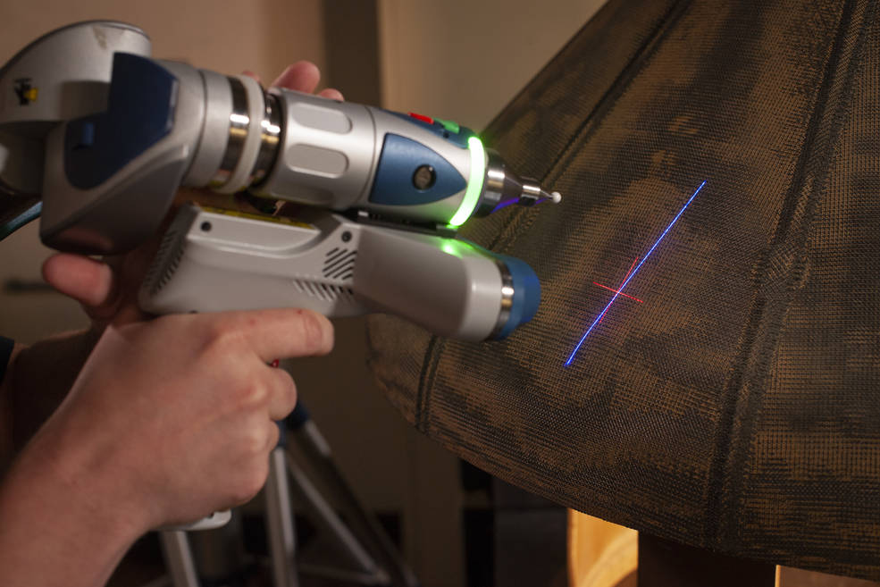 A researcher holding up a device to the HEEET material, shining a light on it.