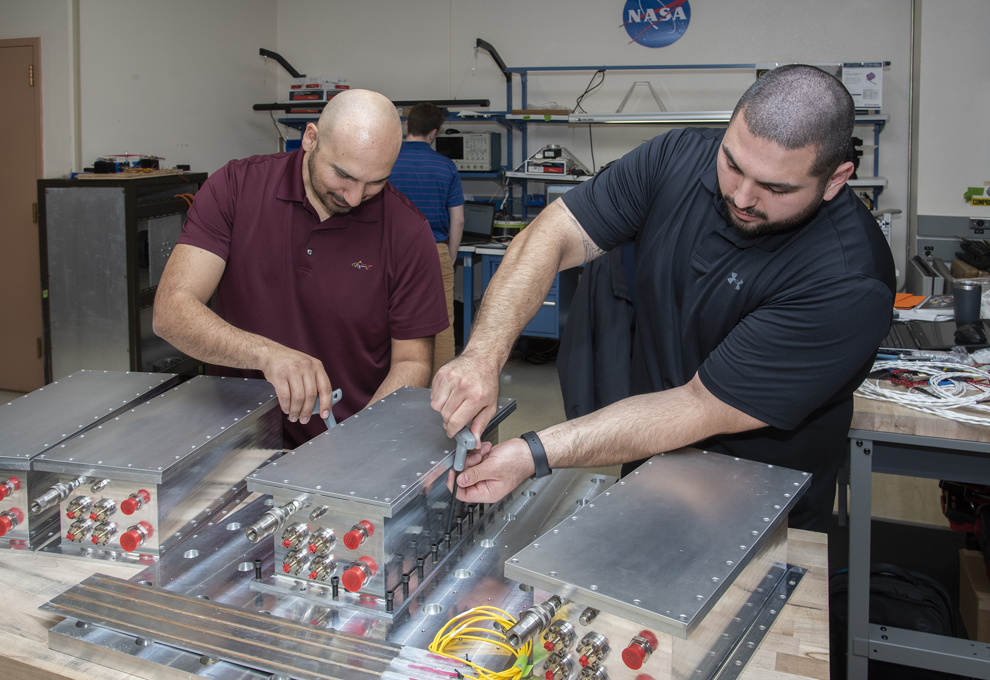 Frank Pena and Jonathan Lopez work on securing a Fiber Optic Sensing System unit developed at NASA AFRC.