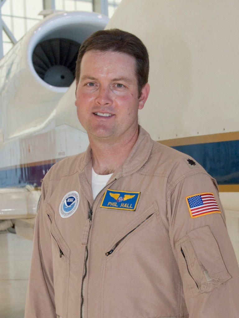 Man in flight suit posed in front of aircraft.