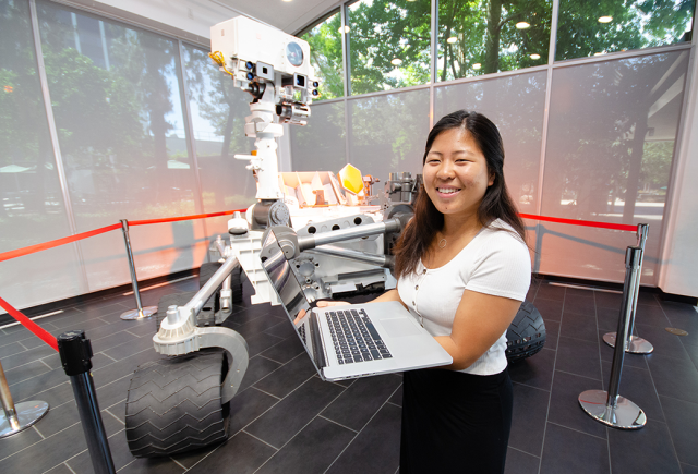 Summer intern Vivian Li poses with a life-size model of the Curiosity Mars rover