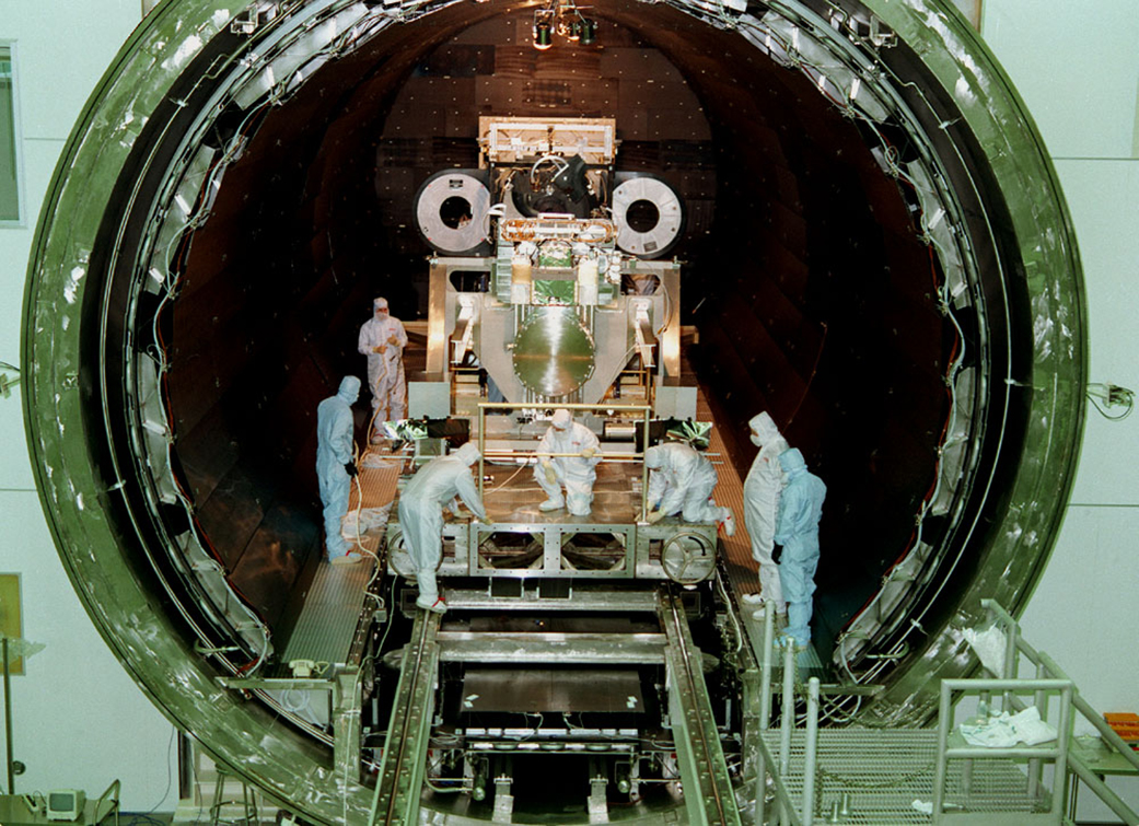 Engineers in the X-ray Calibration Facility – now the world-class X-ray & Cryogenic Facility – at NASA’s Marshall Space Flight Center in Huntsville, Alabama, integrate the Chandra X-ray Observatory’s High Resolution Camera with the mirror assembly inside a 24-foot-diameter vacuum chamber, in this photo taken March 16, 1997. Chandra was launched July 23, 1999, aboard space shuttle Columbia. (NASA) Engineers in head-to-toe cleanroom suits conduct final integration of the Chandra X-ray Observatory’s sensitive camera equipment and high-powered mirror assembly, working inside a mammoth, tube-like vacuum chamber at NASA’s Marshall Space Flight Center.