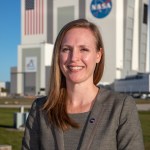 Kennedy Space Center's Allison Mjoen is photographed with the Vehicle Assembly Building in the background.