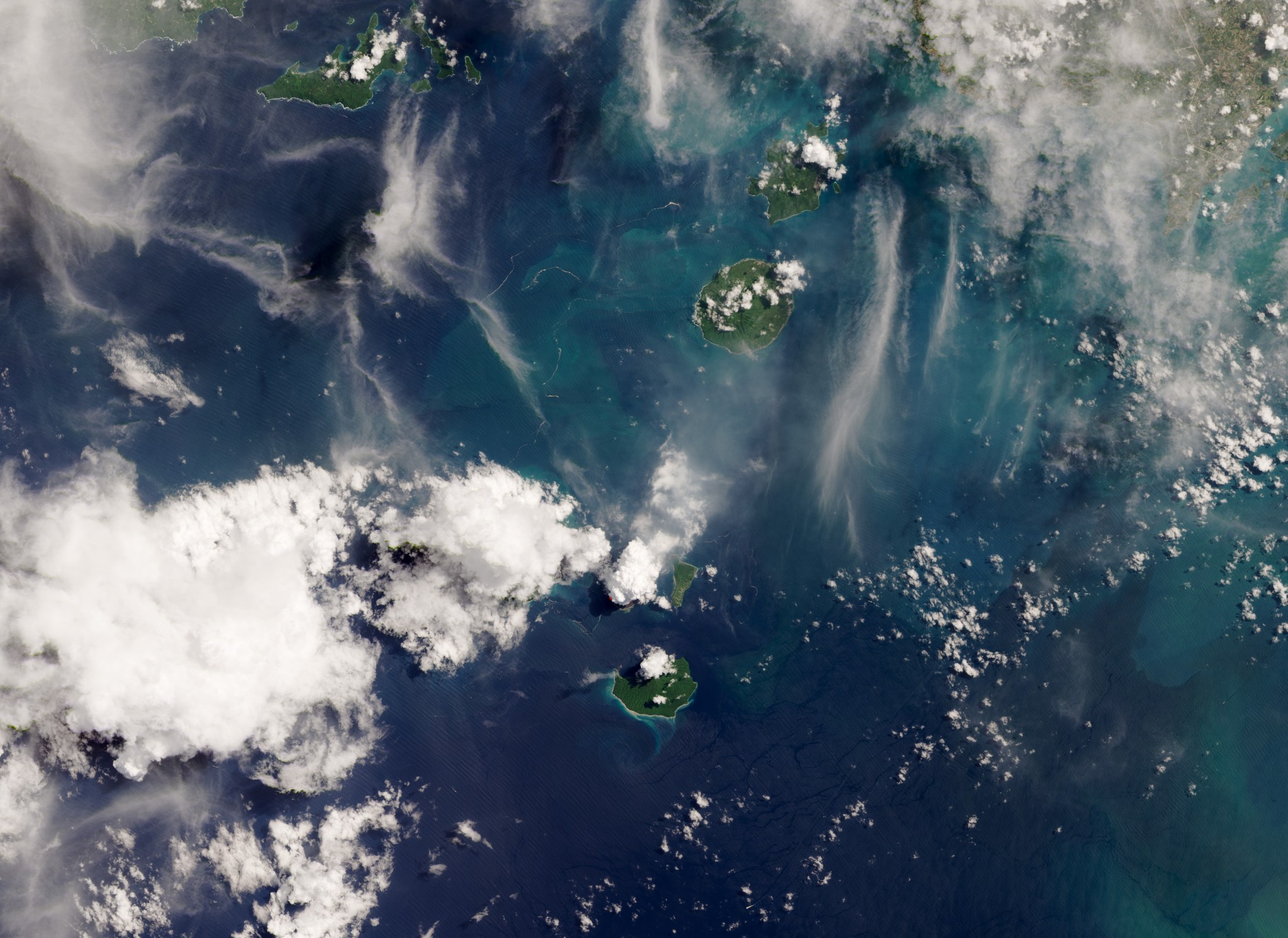 Viewed from above, white volcanic ash billows into the sky.