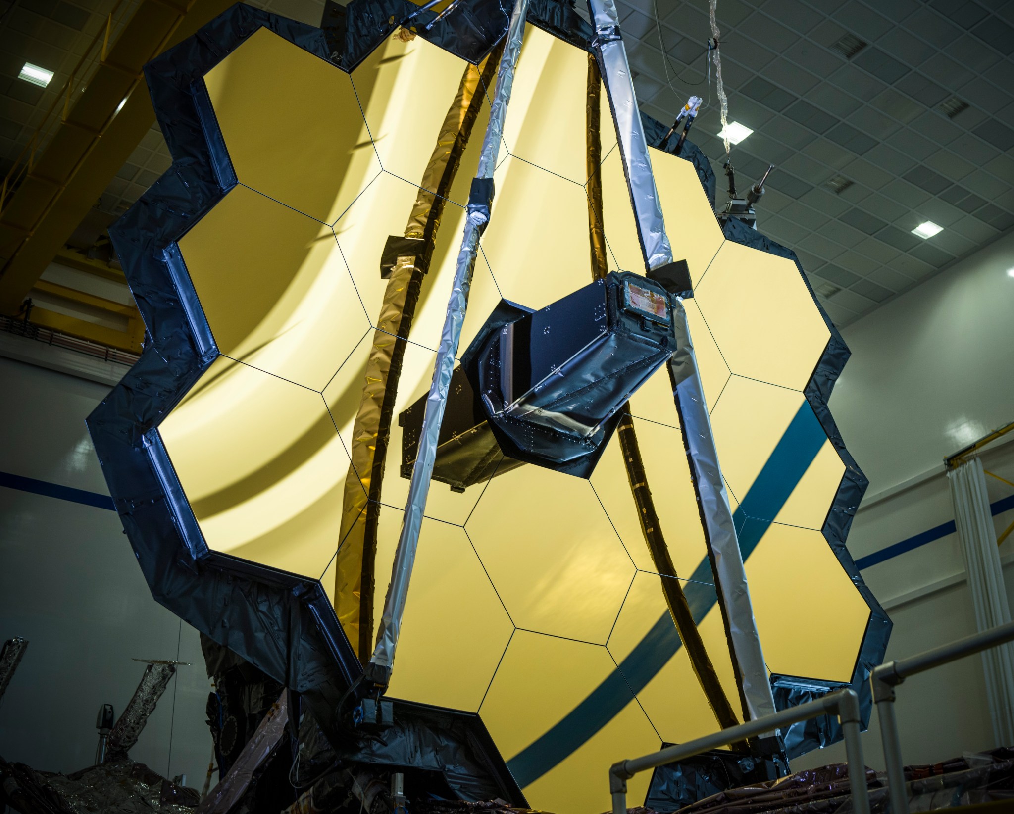 The Webb telescope primarily features a giant, golden hexagonal mirror made out of 18 segments. These segments surround a central black nosecone.
