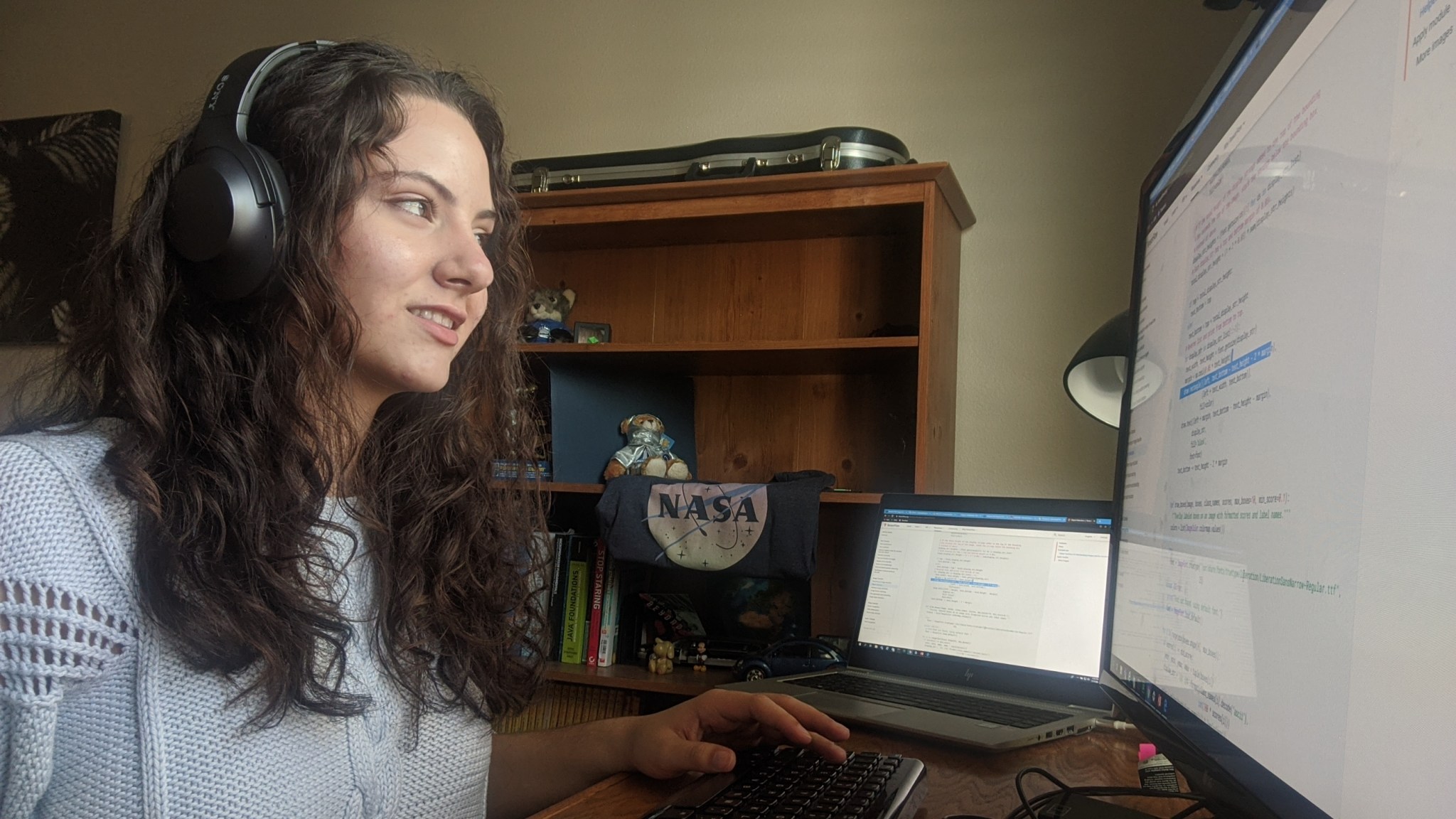 Young woman wearing headset and sitting in front of computer monitors.