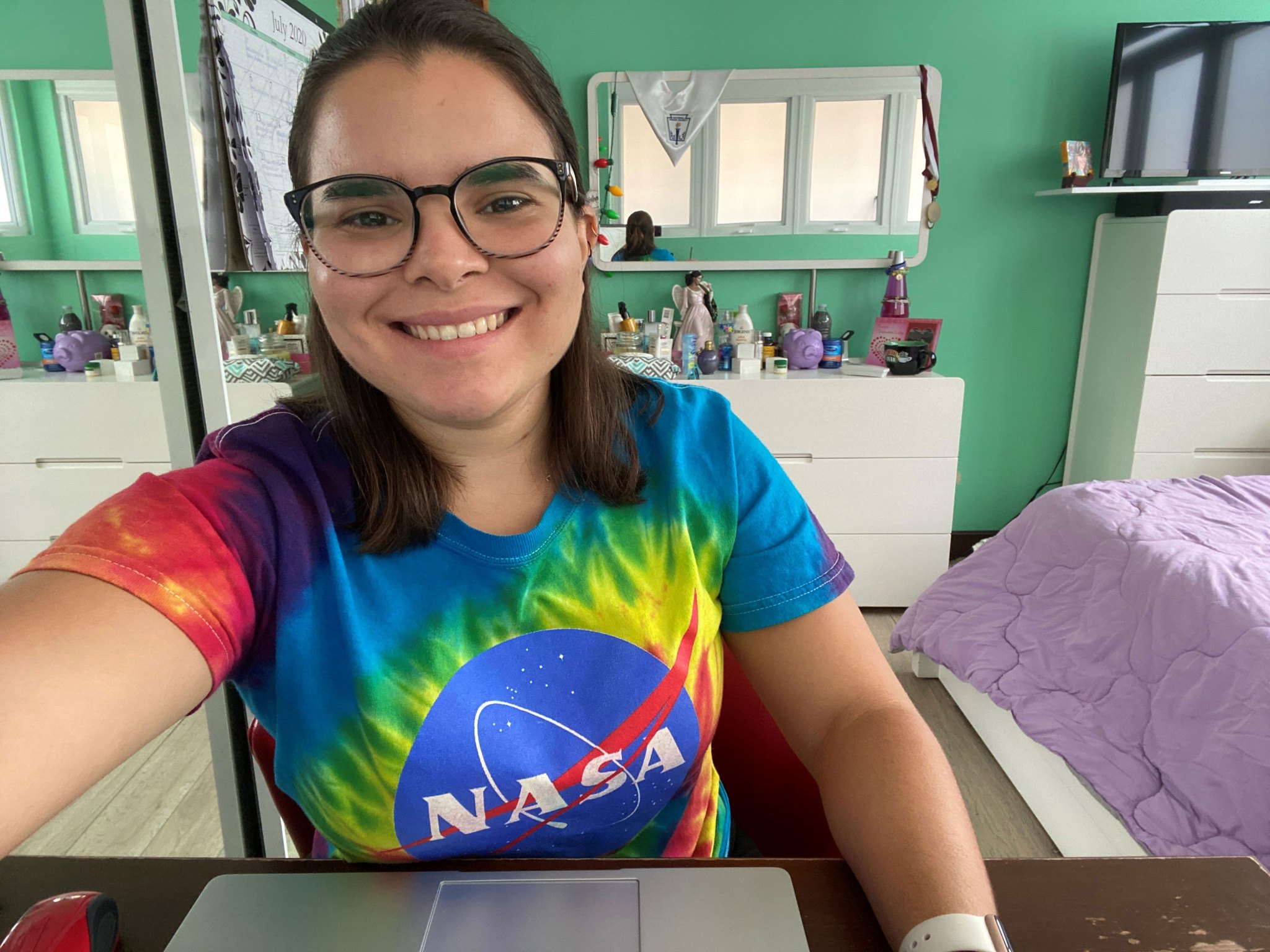 Female college student wearing a brightly colored NASA t-shirt smiling toward the viewer.
