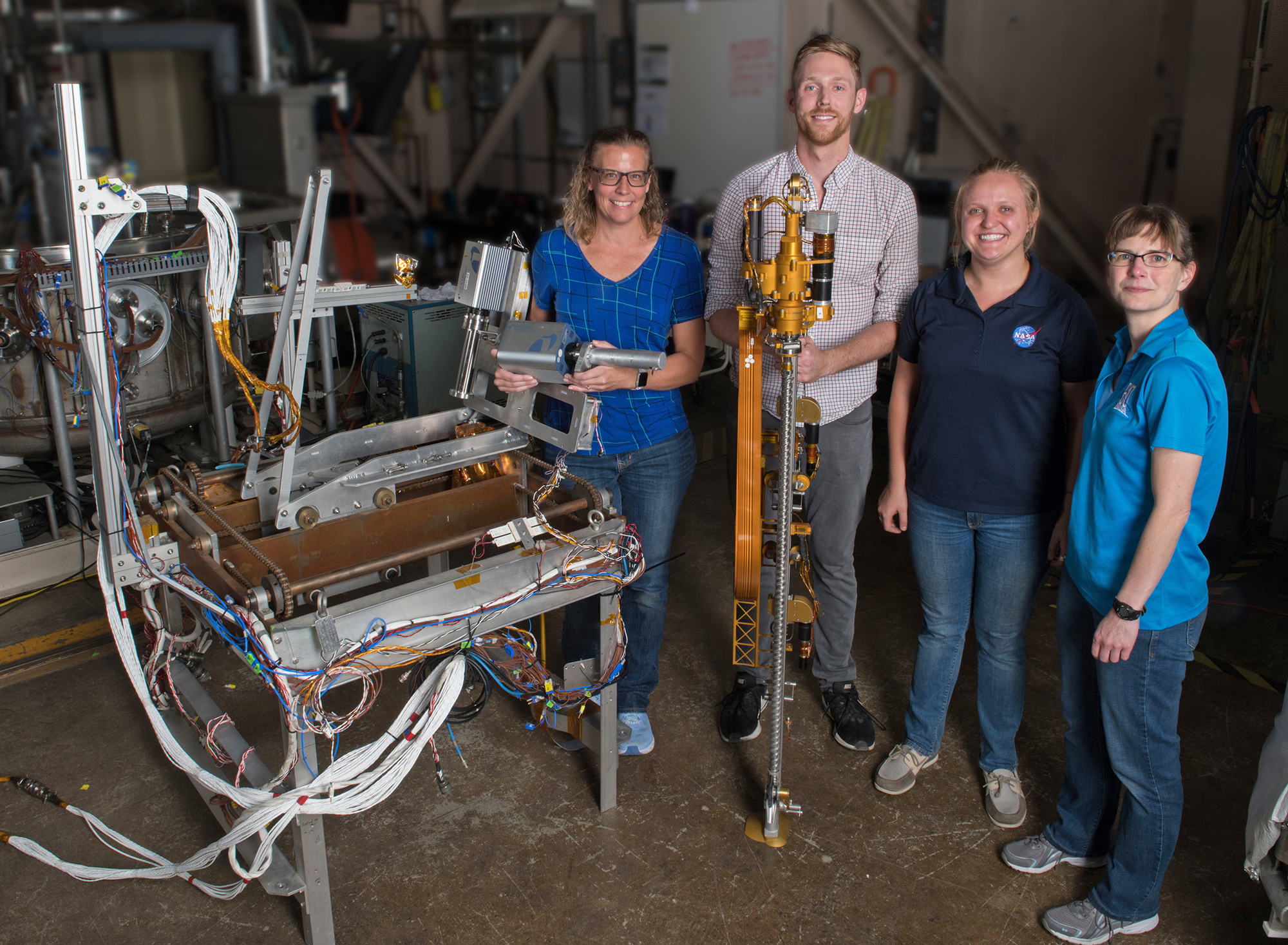 The PRIME-1 thermal vacuum chamber test team stand with TRIDENT and the test trolley.