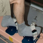 Photo of astronaut on the ISS using foot restraints to help keep him in place.