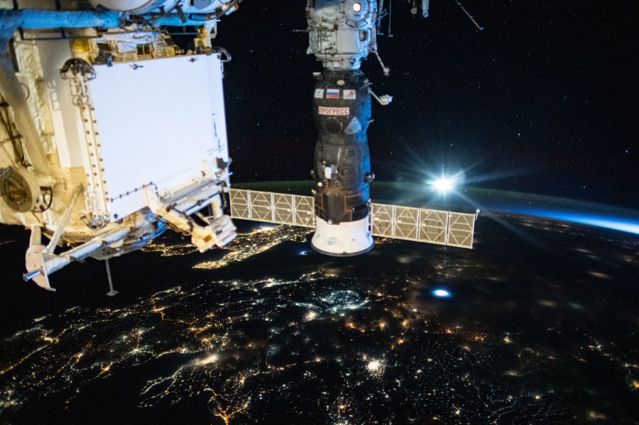 Russia's Progress 76 resupply ship is pictured docked to the International Space Station's Pirs docking compartment. Below the orbiting lab are the city lights of southeastern Europe.