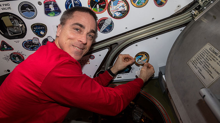 Expedition 63 Commander Chris Cassidy applies a mission sticker inside the space station to signify the departure of Japan's HTV-9 resupply ship from the U.S. Harmony module.