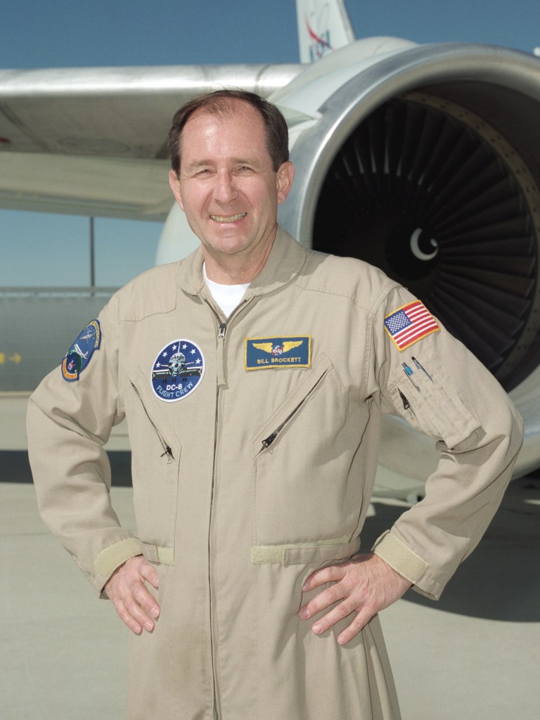 Man in flight suit posing in front of aircraft.