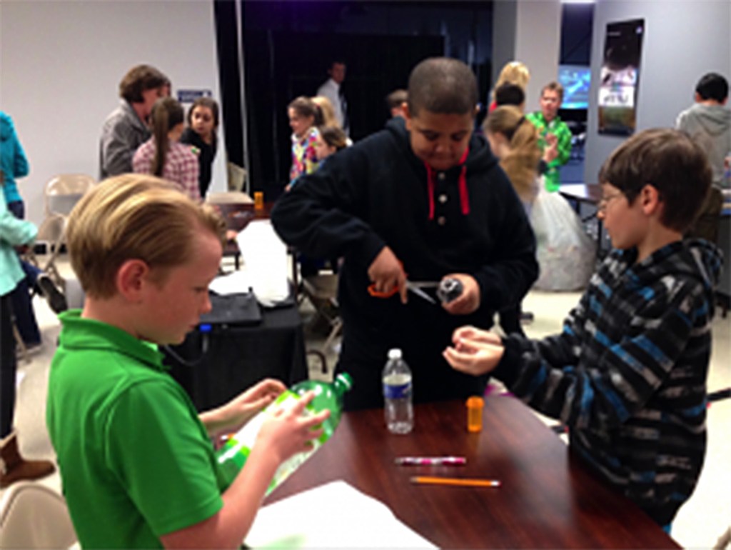 Students cut plastic water bottles with scissors