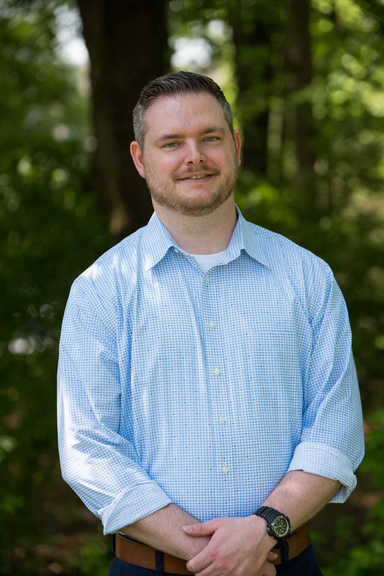 Josh Stevens, wearing a light blue shirt against a backdrop of trees