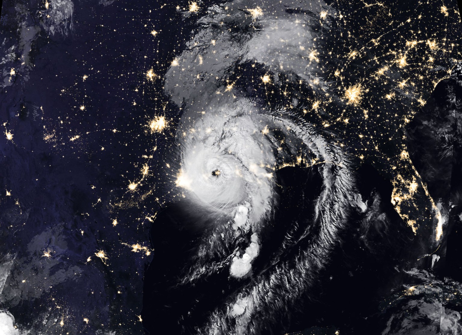 Satellite image of Hurricane Laura over the Gulf Coast at night with citty lights.
