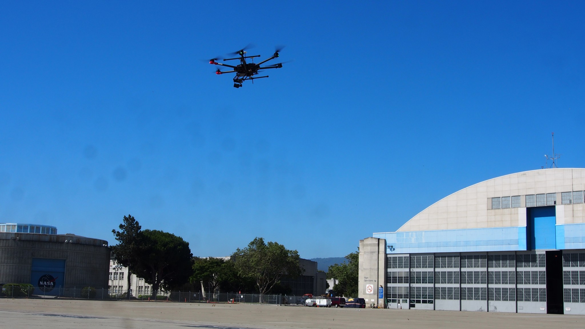 A drone in flight against blue skies.