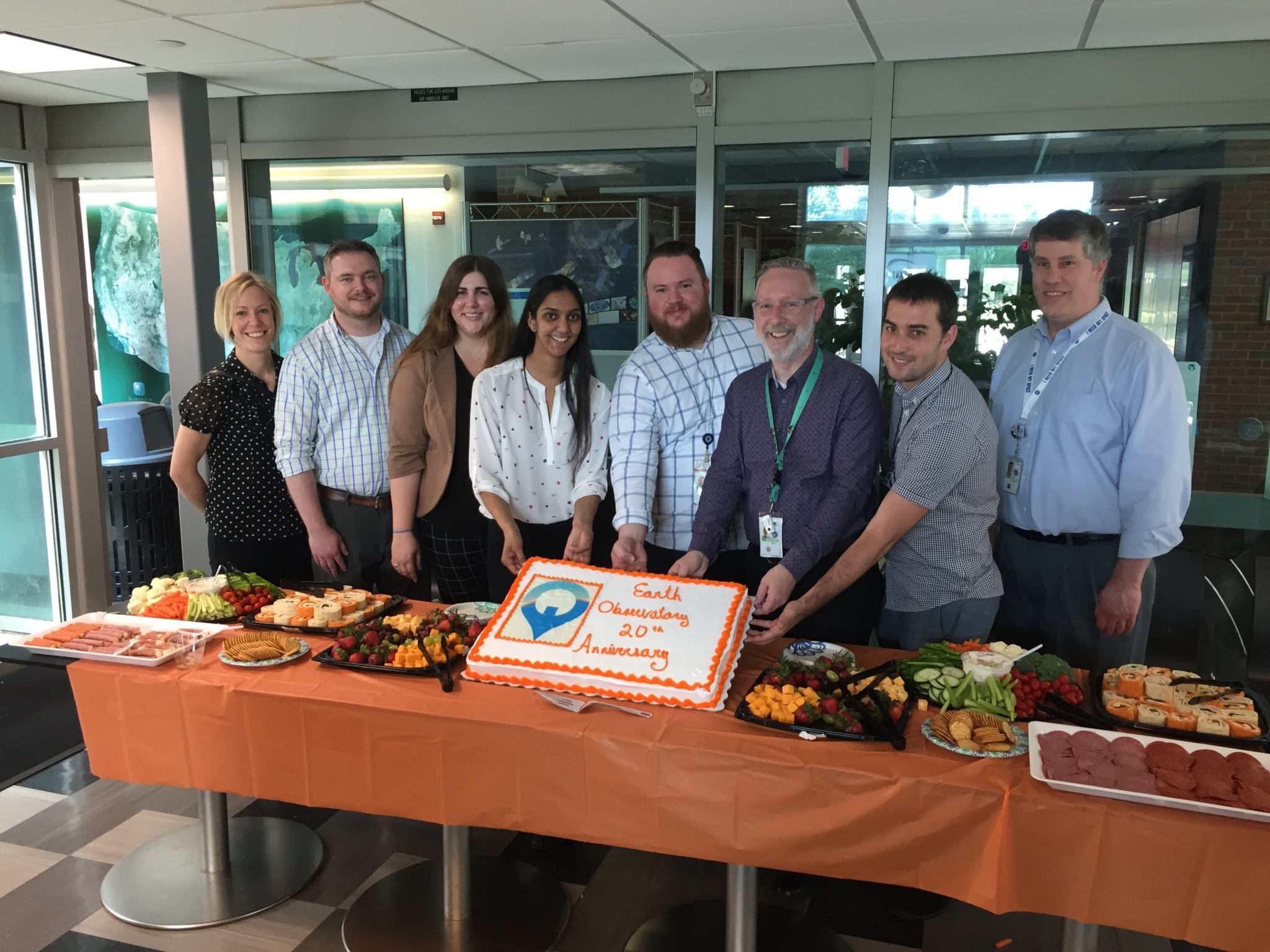 members of the EO team stand behind a table and pose with a cake