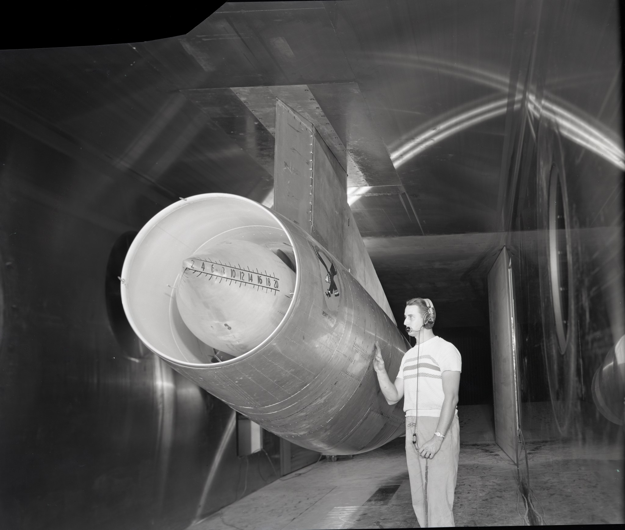 Man standing with large jet engine in wind tunnel test section.