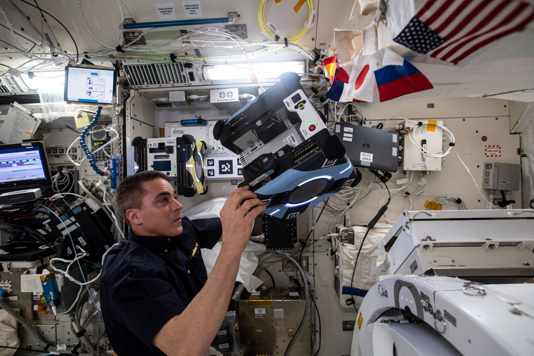 Expedition 63 Commander Chris Cassidy prepares an Astrobee free flying robotic system for Japan Aerospace Exploration Agency