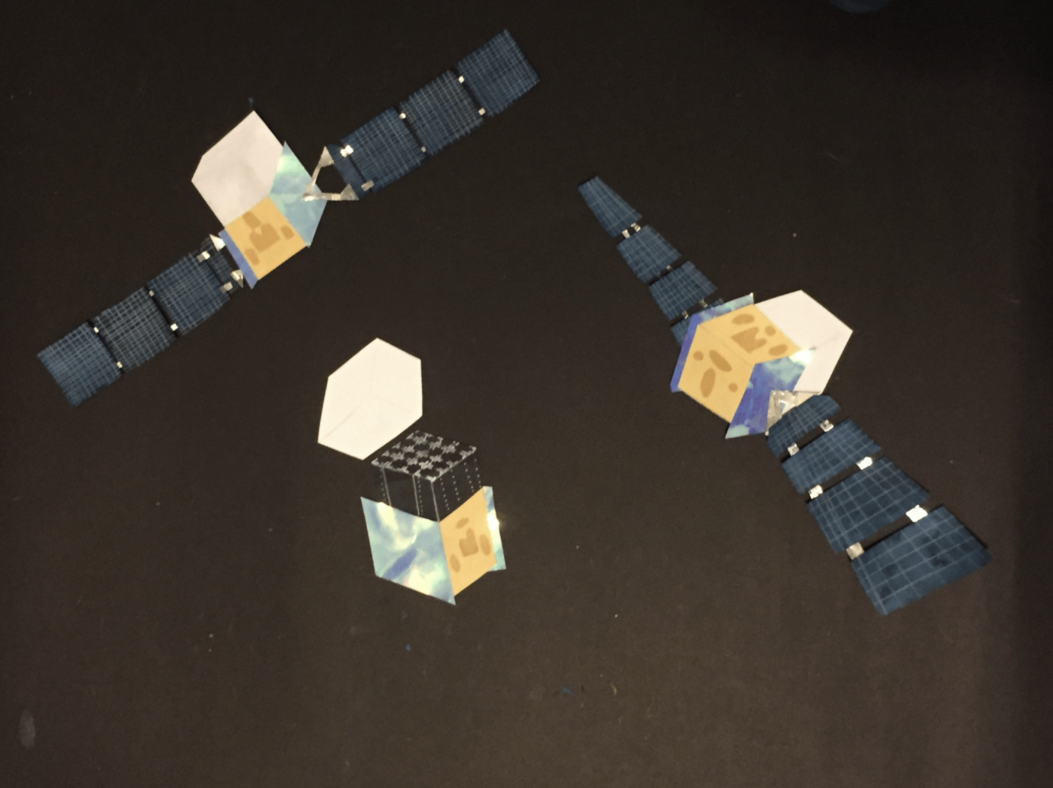 three images of a spacecraft created from cut paper