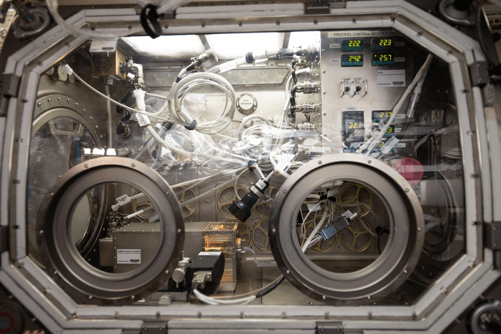 Clear panel with two circular “arm holes.” Behind the panel are many wires and sensors.