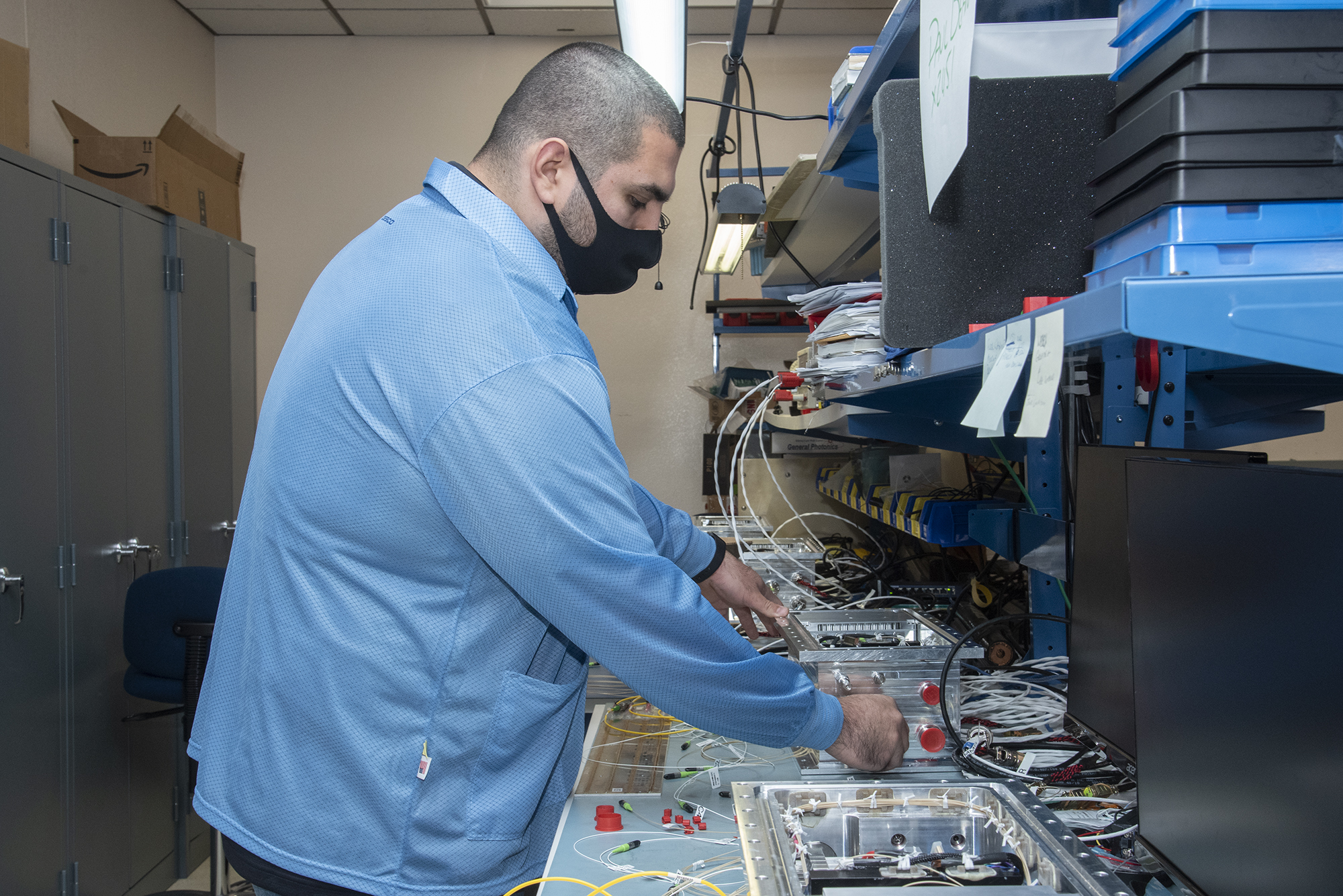 NASA research engineer Jonathan Lopez works on preparing a Compact Fiber Optic Sensing System unit.