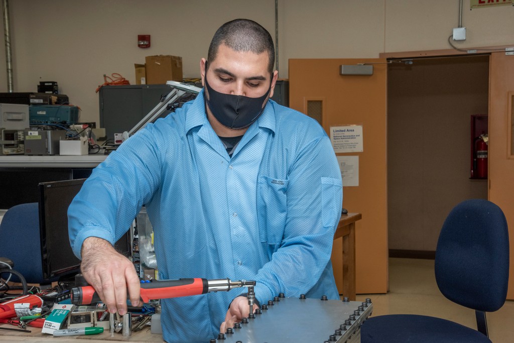 Bolts are torqued on a Compact Fiber Optic Sensing System unit, also known as a FOSS rocket box.