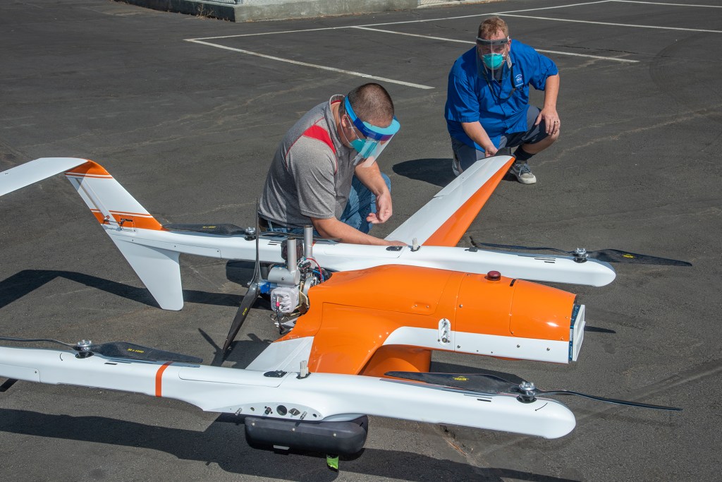 Derek Abramson and Robert Jensen install one of two wings on the Hybrid Quadrotor 90C (HQ-90).