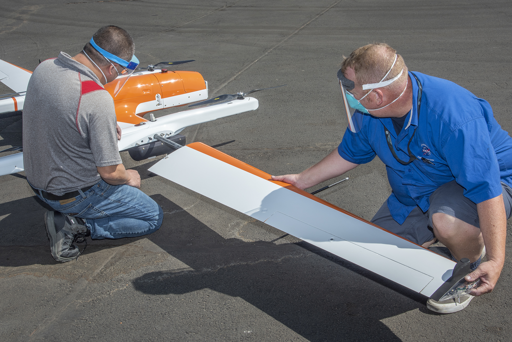 Derek Abramson and Robert Jensen install a wing on the Hybrid Quadrotor 90C (HQ-90).