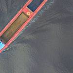 Barge driving through a canal as seen from top down