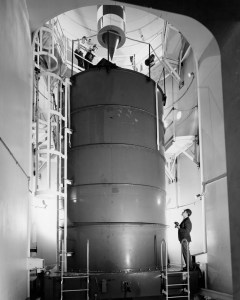 Black and white image of researcher, wearing hard hat, looking up in the zero-g facility.