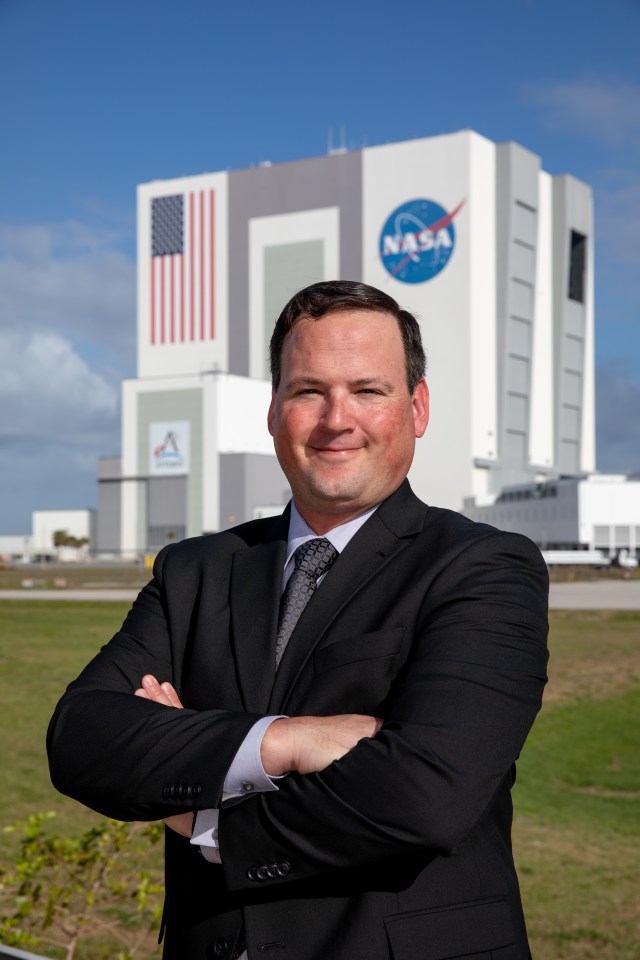 A photo of Kennedy Space Center's Wes Mosedale with the Vehicle Assembly Building in the background.