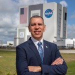 A photo of Kennedy Space Center's Danny Zeno with the Vehicle Assembly Building in the background.