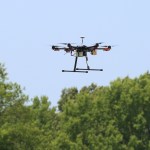Drone hovering in the sky above treeline