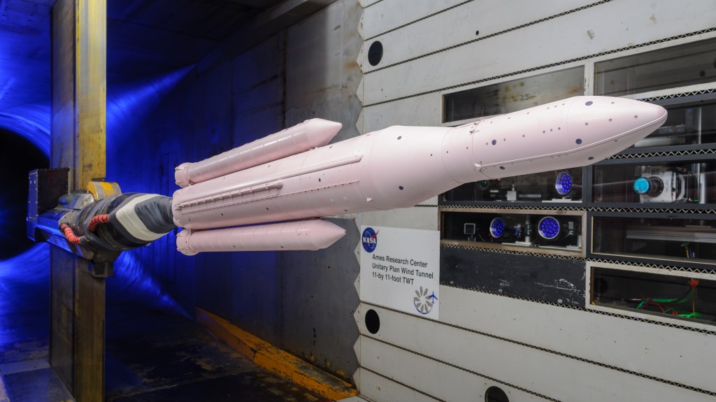 model of Space Launch System rocket painted pink in wind tunnel blue light behind it