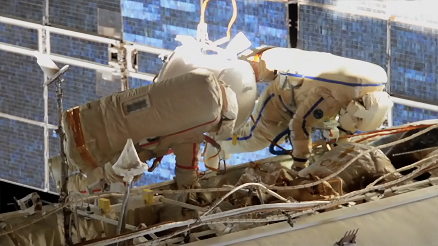 An external station camera captures spacewalkers (from left) Sergey Ryzhikov and Sergey Kud-Sverchkov readying the orbiting lab for a new Russian module.