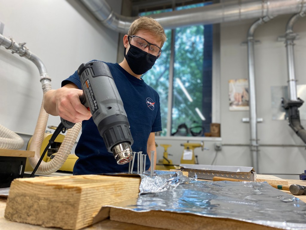 Student using a heat gun to “train” a shape memory alloy wire.