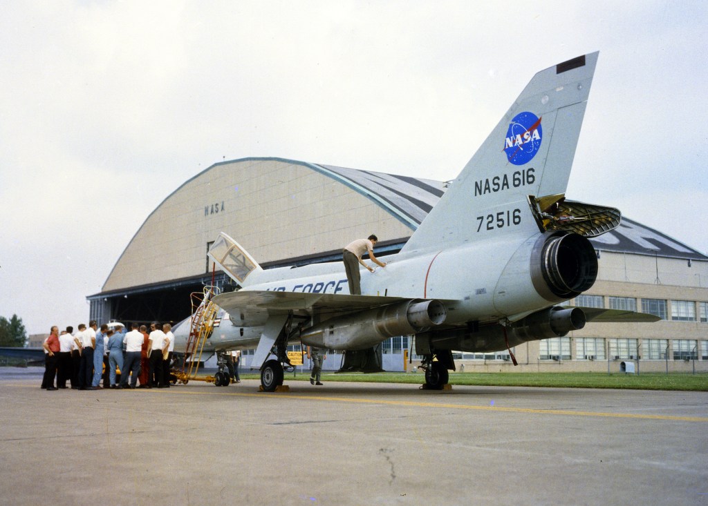 Jet fighter parked in front of hangar.