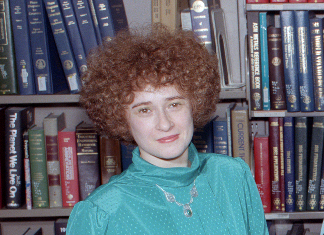 Woman in front of bookcase.