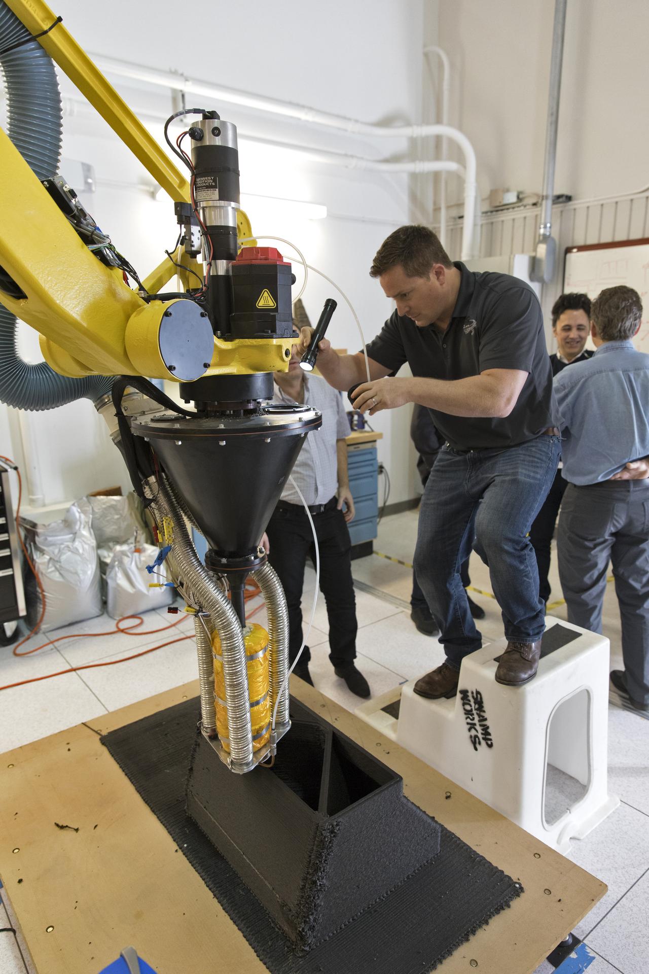 Nathan Gelino examines a Zero Launch Mass 3-D printer