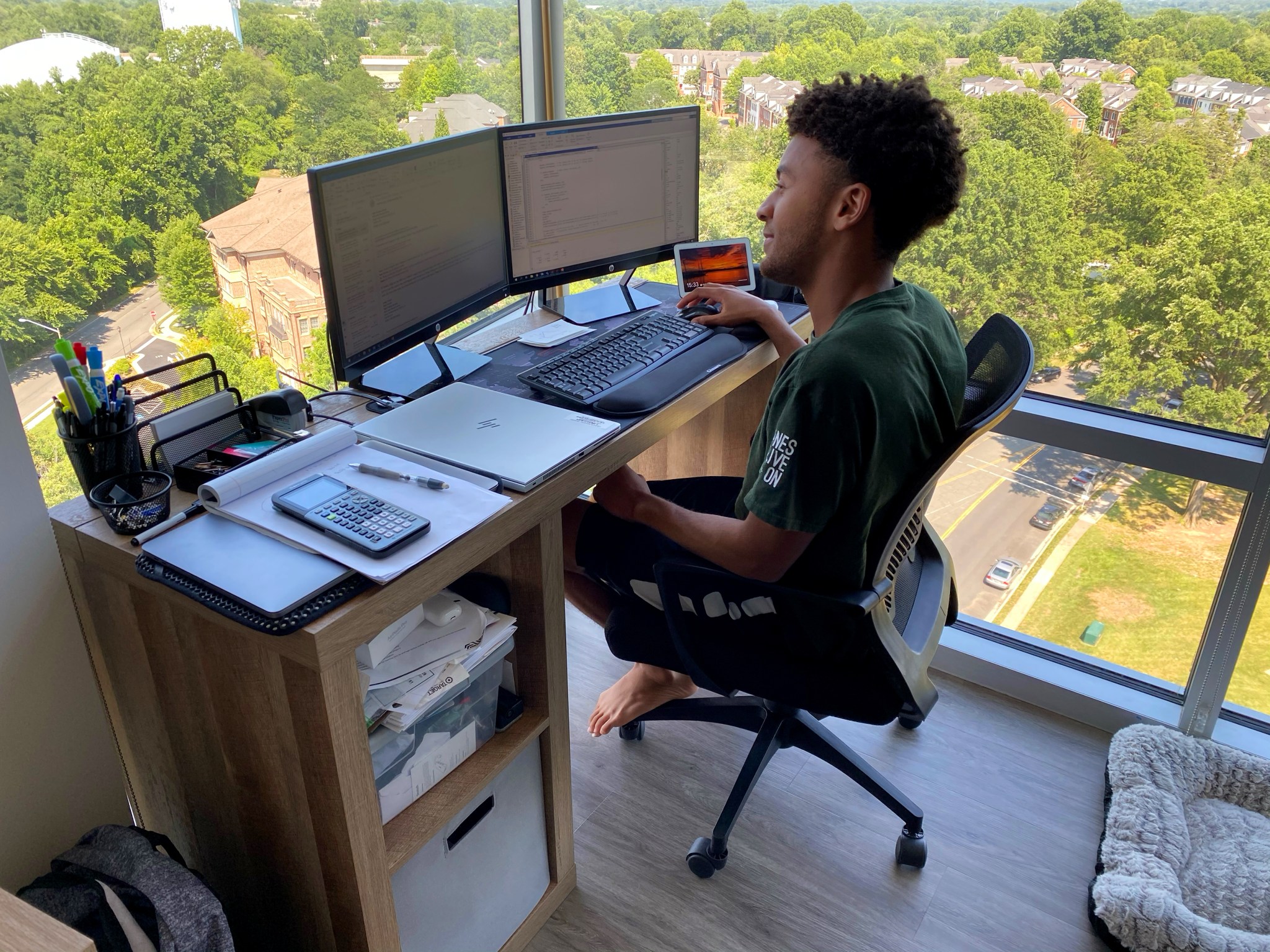 College student is pictured working at a computer in his high-rise apartment.