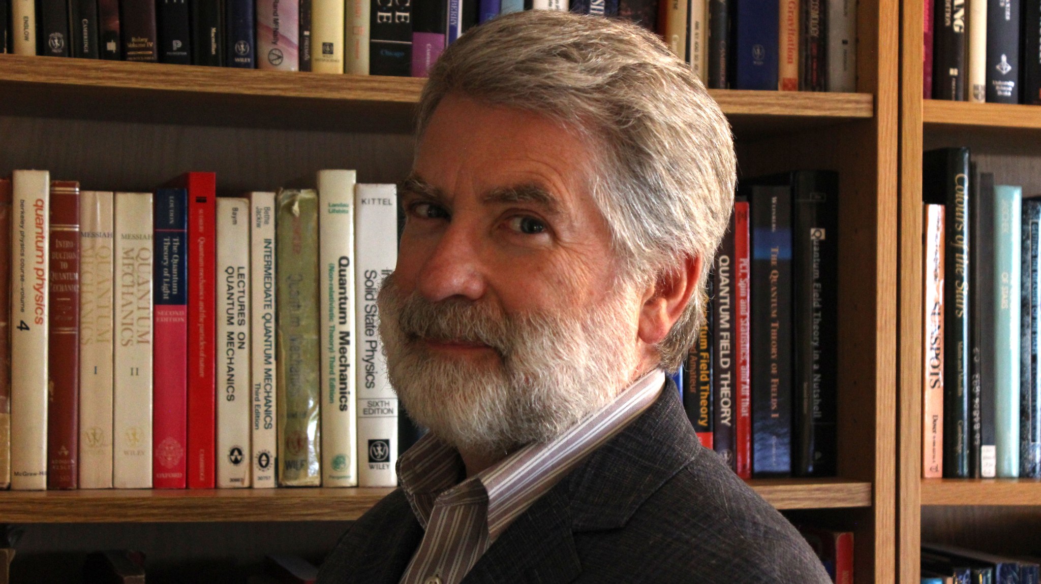 Headshot of Michael Menzel standing in front of bookshelves